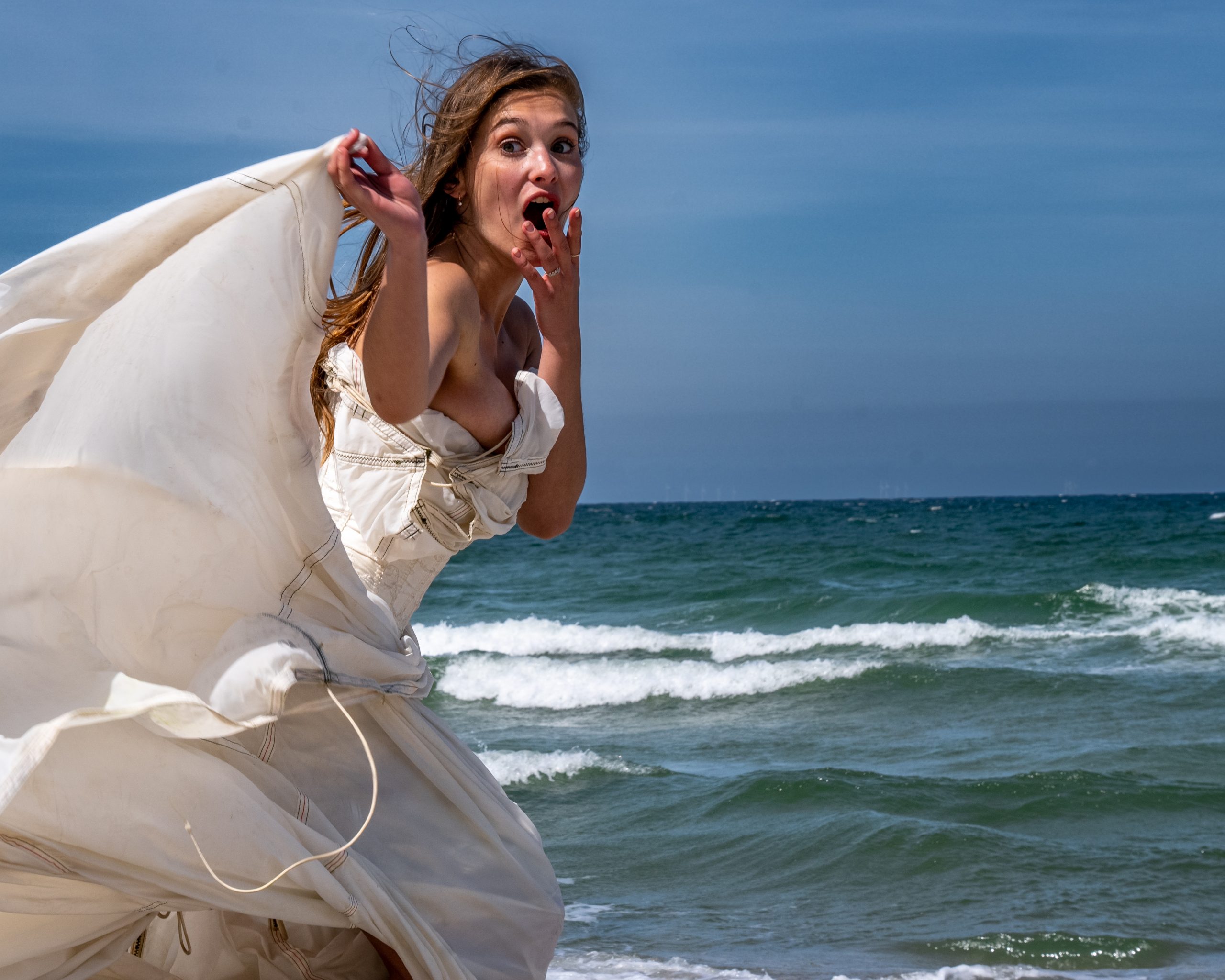 Model am Strand mit wehendem Fallschirm im Wind