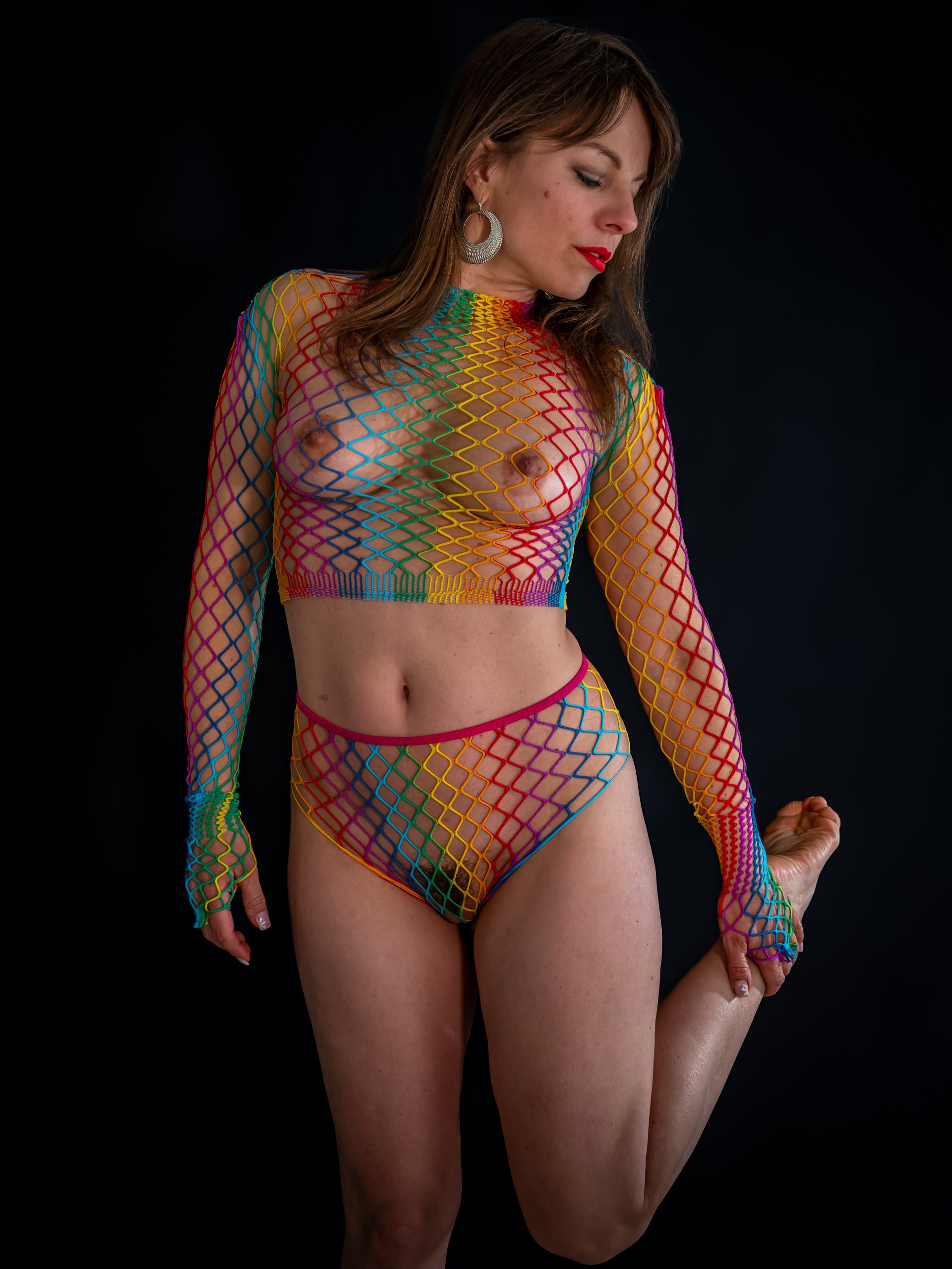 Fashionporträt einer Frau vor schwarzem Hintergrund in einem farbenfrohen grafischen Netzensemble, fotografiert von Henry Freisinger mit kontrastreichem Studiolicht.